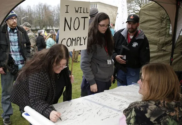 People line up to sign a “declaration of affirmation” as gun rights advocates rally against Initiative 594 at the state capitol in Olympia, Washington December 13, 2014. (Photo by Jason Redmond/Reuters)