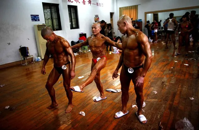 Feng Qing Yu (C), 61, prepares to compete in a bodybuilding competition next to his bother Feng Qing Ji (R), 69, and Jin He, 57, in Shaoxing, Zhejiang province April 20, 2013. Amateur male and female bodybuilders from clubs around Shaoxing city competed in a one-day event to promote the sport. Categories range from “Mr. Fitness man” to “Grand Old man” –  for male participants over fifty years old. Every contestant to take first prize received a medal, diploma and 1000 rmb ($160) in cash. (Photo by Carlos Barria/Reuters)