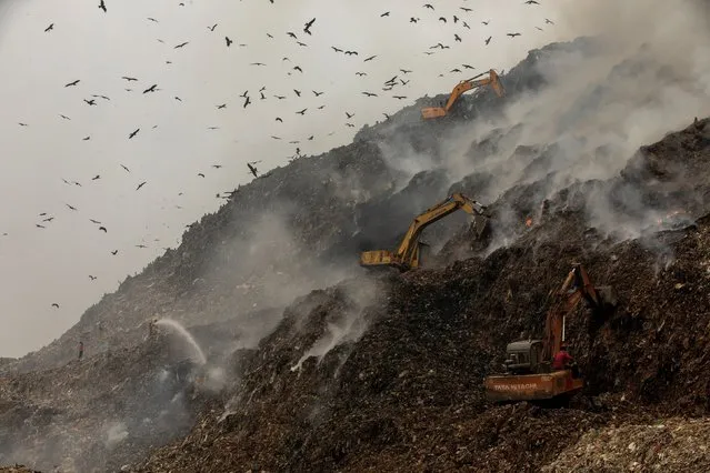 Firefighters and excavators try to douse fire as smoke billows from burning garbage at the Ghazipur landfill site in New Delhi, India, November 25, 2020. (Photo by Danish Siddiqui/Reuters)
