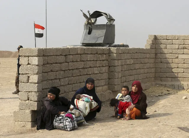 Civilians wait for clashes to end to go to displaced people camps, in the village of Tob Zawa, about 9 kilometers (5.6 miles) from Mosul, Iraq, Tuesday, October 25, 2016. (Photo by Khalid Mohammed/AP Photo)