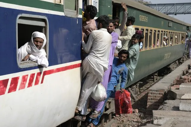 People ride on an overcrowded passenger train to reach their villages and cities to celebrate the upcoming Eid al-Fitr holidays, marking the end of the Islamic holy month of Ramadan, in Lahore, Pakistan, Thursday, April 20, 2023. (Photo by K.M. Chaudary/AP Photo)