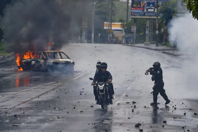 A police officer aims his shotgun at two men riding a motorcycle during a protest against Nicaragua's President Daniel Ortega in Managua, Nicaragua, Monday, May 28, 2018. Violence returned to Nicaragua when riot police confronted protesters and students seized a university. (Photo by Esteban Felix/AP Photo)