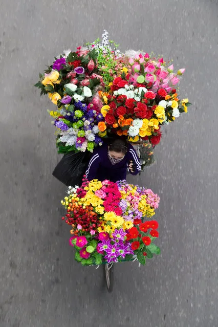 “Buoi, the woman carrying the fake flowers, walks 10km every day. She is a Christian and wanted to go home for Christmas but it is difficult to earn extra money at the end of the year, when the demand for fake flowers is not very high”. (Photo by Loes Heerink/The Guardian)
