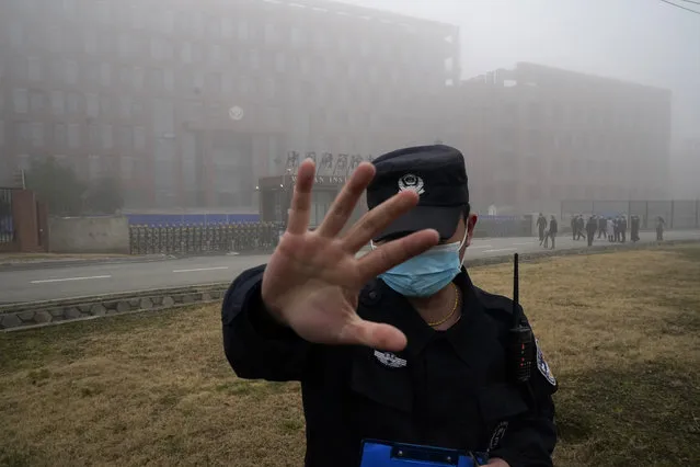 A security person moves journalists away from the Wuhan Institute of Virology after a World Health Organization team arrived for a field visit in Wuhan in China's Hubei province on Wednesday, February 3, 2021. The WHO team is investigating the origins of the coronavirus pandemic has visited two disease control centers in the province. (Photo by Ng Han Guan/AP Photo)