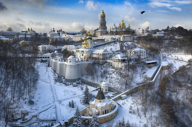 A bird flies over the sky near the 1000-year old Orthodox Monastery of Caves covered with the first snow this winter in Kyiv, Ukraine, Friday, January 15, 2021. Ukraine has been hit with unusually cold weather with temperatures of 21 degrees Celsius below zero (69.8 F). (Photo by Efrem Lukatsky/AP Photo)