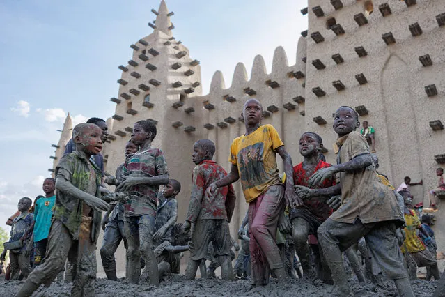 Children help during the re-plastering of the Great Mosque of Djenne in central Mali on June 3, 2023. (Photo by Ousmane Makaveli/AFP Phoot)