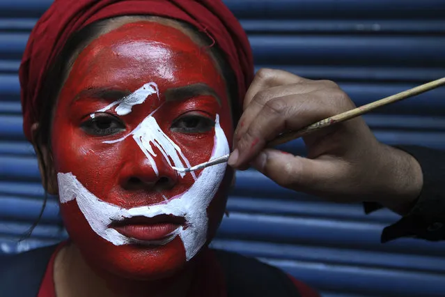 A supporter of a faction of the ruling Nepal Communist Party (NCP) gets her face painted before taking part in a “victory” rally after yesterday's Supreme Court ruling to overturn the prime minister's decision to dissolve parliament, in Kathmandu on February 24, 2021. (Photo by Prakash Mathema/AFP Photo)
