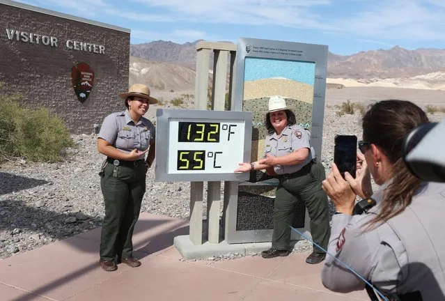 National Park Service Rangers Gia Ponce (L) and Christina Caparelli are photographed by Ranger Nicole Bernard next to a digital display of an unofficial heat reading at Furnace Creek Visitor Center during a heat wave in Death Valley National Park in Death Valley, California, on July 16, 2023. Tens of millions of Americans braced for more sweltering temperatures Sunday as brutal conditions threatened to break records due to a relentless heat dome that has baked parts of the country all week. By the afternoon of July 15, 2023, California's famous Death Valley, one of the hottest places on Earth, had reached a sizzling 124F (51C), with Sunday's peak predicted to soar as high as 129F. (Photo by Ronda Churchill/AFP Photo)