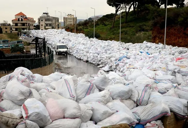 A van drives past piles of wrapped garbage blocking a newly-opened road in the town of Jdeideh northeast of Beirut on January 4, 2016. (Photo by Joseph Eid/AFP Photo)