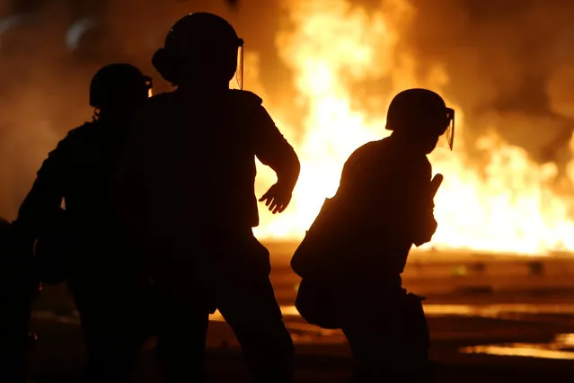 Riot policemen clashing with anti-government demonstrators, are pictured next to burning barricades during a protest against a constitutional amendment, known as PEC 55, that limit public spending, in front of Brazil's National Congress in Brasilia, Brazil, November 29, 2016. (Photo by Adriano Machado/Reuters)