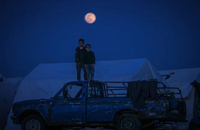 Syrian kids stand on a vehicle as full moon rises over Maarrat Misrin camp in Idlib province, Syria on March 28, 2021. (Photo by Muhammed Said/Anadolu Agency via Getty Images)