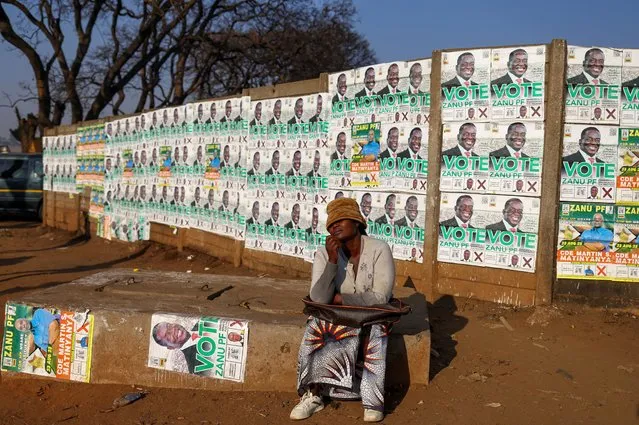 Local resident Linah Shanga sits in front of election posters, ahead of the presidential elections, in Mbare township, in Harare, Zimbabwe on August 21, 2023. (Photo by Siphiwe Sibeko/Reuters)