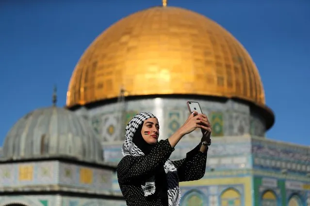 A Palestinian woman takes a selfie as the Dome of the Rock is seen in the background, during Eid al-Fitr prayers, which marks the end of the holy fasting month of Ramadan, at the compound that houses al-Aqsa mosque, known to Muslims as Noble Sanctuary and to Jews as Temple Mount, in Jerusalem's Old City, amid Israel-Gaza fighting May 13, 2021. (Photo by Ammar Awad/Reuters)
