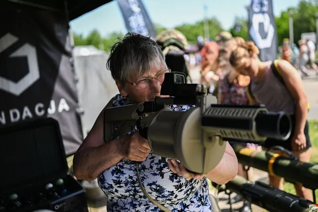 An elderly woman holds a grenade launcher during a military picnic organized by the Foundation GROT and branches of the Polish army on June 19, 2022 in Siemianowice, Poland. As one of NATO's biggest spenders, Poland's ambition to expand defence capabilities to 300,000 personnel – a combination of professional army and part-time volunteers of the Territorial Defence Force, would mean doubling the current number of personnel. (Photo by Omar Marques/Getty Images)
