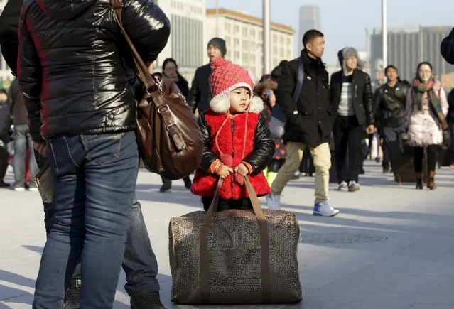 A four-year-old girl holds the bag as she and her parents wait for their train to hometown in Shanxi province, at Beijing Railway station, in Beijing, China, January 25, 2016. (Photo by Jason Lee/Reuters)