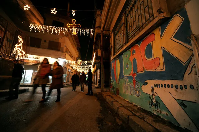 People walk under Christmas decorations during Christmas eve in al-Hamidiyah neighborhood in the old city of Homs, Syria December 24, 2016. (Photo by Omar Sanadiki/Reuters)