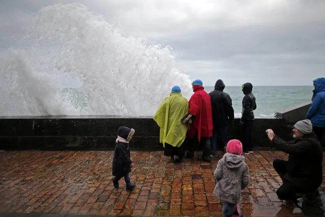 A wave crashes against a sea wall as people gather on the waterfront in Saint Malo, western France, March 22, 2015. (Photo by Stephane Mahe/Reuters)