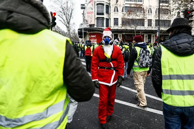 A protester wears a costume of Santa Claus among protesters with yellow vests (gilets jaunes) during a demonstration against rising costs of living they blame on high taxes in Paris, on December 8, 2018. The “yellow vest” movement in France originally started as a protest about planned fuel hikes but has morphed into a mass protest against President's policies and top-down style of governing. (Photo by Sameer Al-Doumy/AFP Photo)