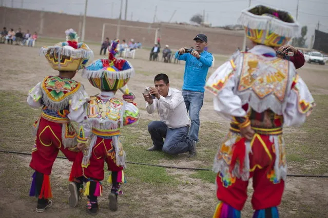 Parents of young "scissors" dancers take pictures of them before performing in a national scissors dance competition in the outskirts of Lima December 1, 2013. (Photo by Enrique Castro-Mendivil/Reuters)