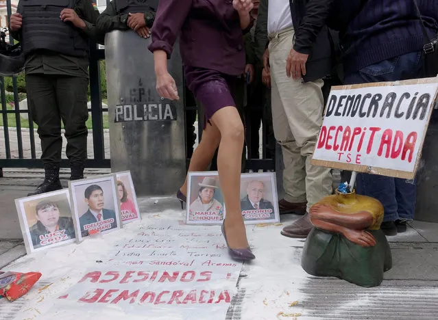 A demonstrator passes through images of Supreme Electoral Court members, as signs read, “Murderers of democracy” and “Decapitated democracy”, during a protest against Bolivia's President Evo Morales' bid for re-election in 2019, in La Paz, Bolivia, December 31, 2018. (Photo by David Mercado/Reuters)