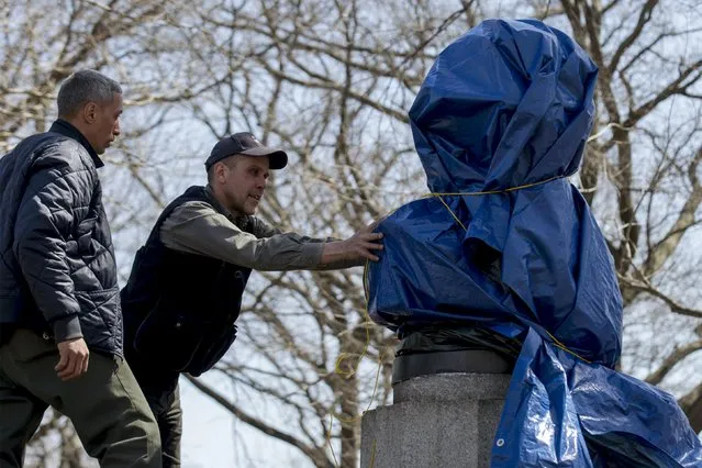 New York City Parks workers work to remove a covered large molded bust of Edward Snowden at Fort Greene Park in the Brooklyn borough of New York April 6, 2015. (Photo by Brendan McDermid/Reuters)