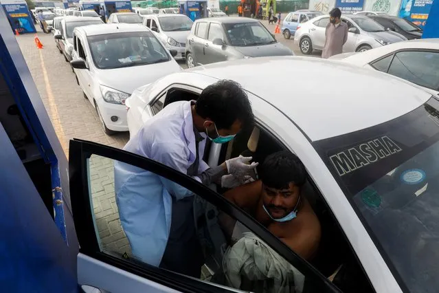 A resident receives a dose of coronavirus disease (COVID-19) vaccine at a drive-through vaccination facility in Karachi, Pakistan on August 3, 2021. (Photo by Akhtar Soomro/Reuters)