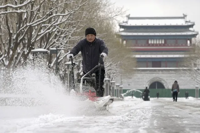 In this photo released by Xinhua News Agency, a worker uses a machine to clear snow of the pavement at Yongdingmen Park in Beijing, Monday, December 11, 2023. An overnight snowfall across much of northern China prompted road closures and the suspension of classes and train service on Monday. (Photo by Li Xin/Xinhua via AP Photo)