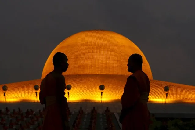 A Buddhist monk stands in front of the Wat Phra Dhammakaya temple in Pathum Thani province, north of Bangkok before a ceremony on Makha Bucha Day February 22, 2016. (Photo by Jorge Silva/Reuters)