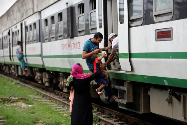 Men help a child to board the train at Kamalapur Railway Station in Dhaka, Bangladesh, August 7, 2016. (Photo by Mohammad Ponir Hossain/Reuters)
