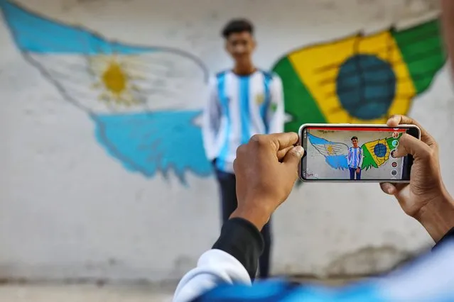 An Argentina fan takes a photo in front of a graffiti ahead of FIFA World Cup Qatar 2022 in Dhaka, Bangladesh on November 18, 2022. (Photo by Mohammad Ponir Hossain/Reuters)