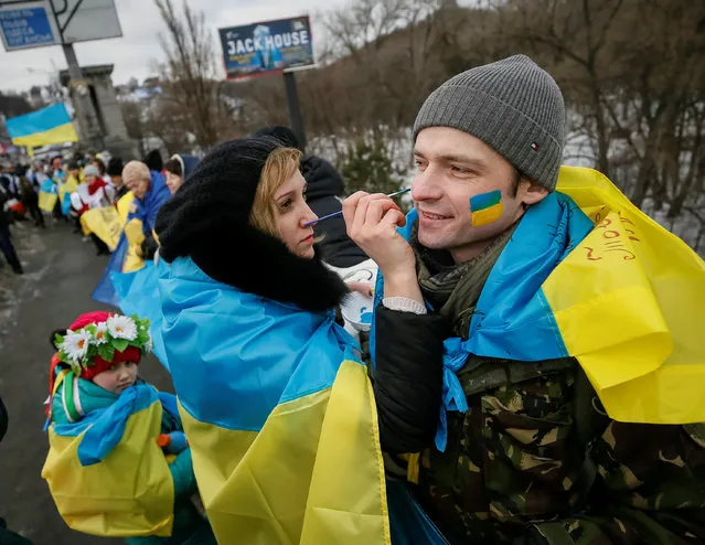 A woman paints the colors of the Ukrainian national flag on a man's face during celebrations for Unity Day in Kiev, Ukraine, January 22, 2017. (Photo by Gleb Garanich/Reuters)