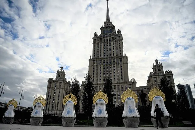A man takes a picture of the “Matryoshki art object”, seven mirrored traditional Russian nesting dolls “matryoshka” topped with “kokoshnik” headdresses, in front of Soviet-era skyscraper “Ukraina” hotel in downtown Moscow on September 9, 2021. (Photo by Kirill Kudryavtsev/AFP Photo)