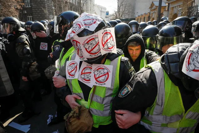 Police officers with stickers put by activists of Ukrainian nationalist parties block a street during a rally to demand an investigation into the corruption of Ukraine's armed forces officials, in Kiev, Ukraine March 9, 2019. The stickers read “Poroshenko's Svinarchuks behind bars”. (Photo by Gleb Garanich/Reuters)