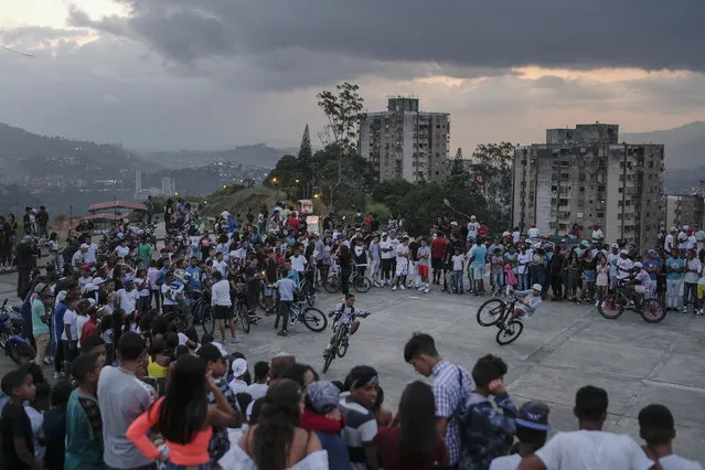 Youths perform wheelies on their bikes during an exhibition in the Petare neighborhood of Caracas, Venezuela, Sunday, September 19, 2021. (Photo by Matias Delacroix/AP Photo)