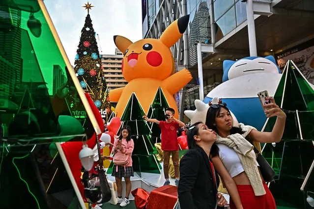 People take pictures with a Pokemon-themed Christmas display in front of the Central World shopping mall in Bangkok on December 25, 2023. (Photo by Lillian Suwanrumpha/AFP Photo)