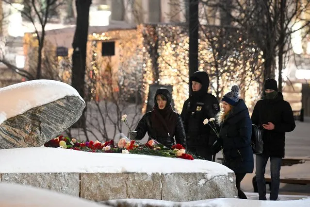 People lay flowers paying their last respect to Alexei Navalny at the monument, a large boulder from the Solovetsky islands, where the first camp of the Gulag political prison system was established, on Friday, February 16, 2024. Russian authorities say that Alexei Navalny, the fiercest foe of Russian President Vladimir Putin who crusaded against official corruption and staged massive anti-Kremlin protests, died in prison. He was 47. (Photo by Dmitry Serebryakov/AP Photo)