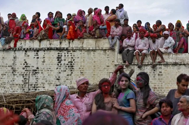 Hindu devotees watch the religious festival of Lathmar Holi, where women beat the men with sticks, in the town of Barsana in the Uttar Pradesh region of India, March 17, 2016. (Photo by Cathal McNaughton/Reuters)