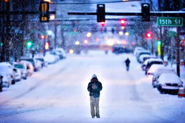 A morning commuter walks in the plowed road as mixed winter precipitation falls Thursday, February 13, 2014, in Philadelphia. (Photo by Matt Rourke/AP Photo)