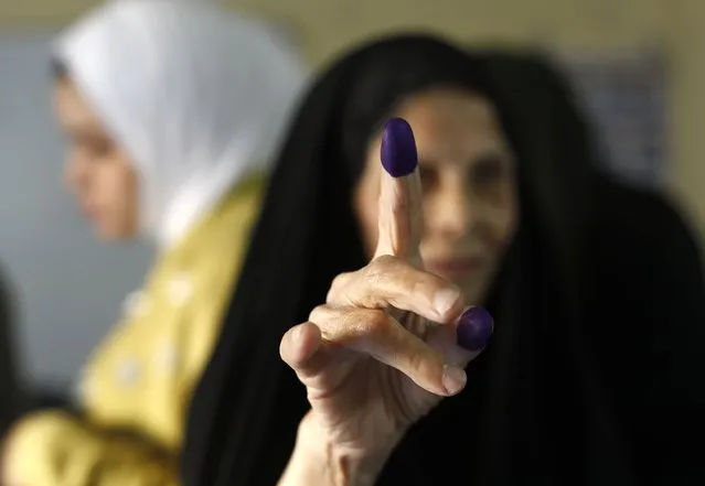 An Iraqi elderly woman shows her ink-stained finger after casting her vote inside a polling station in the country's parliamentary elections in Baghdad, Iraq, Sunday, October 10, 2021. Iraq closed its airspace and land border crossings on Sunday as voters headed to the polls to elect a parliament that many hope will deliver much needed reforms after decades of conflict and mismanagement. (Photo by Hadi Mizban/AP Photo)