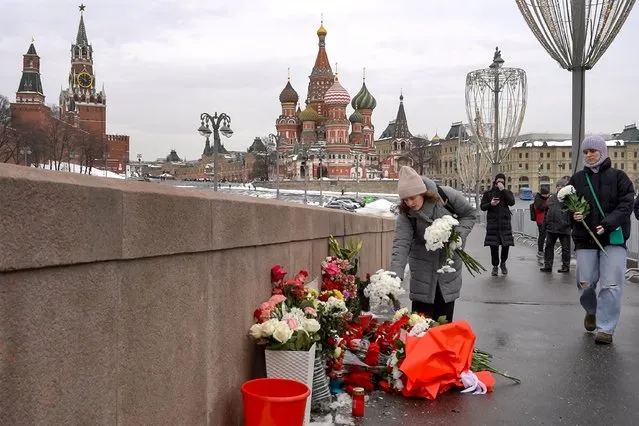 People come to lay flowers at the site where late opposition leader Boris Nemtsov was fatally shot on a bridge near the Kremlin in central Moscow on February 27, 2024, on the 9th anniversary of his assassination. Nemtsov was one of President Vladimir Putin's loudest critics until he was shot and killed on a Moscow bridge near the Kremlin on February 27, 2015. (Photo by Andrey Borodulin/AFP Photo)