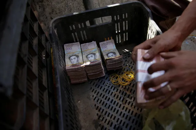 Stacks of 100 bolivar notes are seen in a plastic crate at a stall in a street market near Venezuela's Central Bank in Caracas, Venezuela December 16, 2016. (Photo by Marco Bello/Reuters)