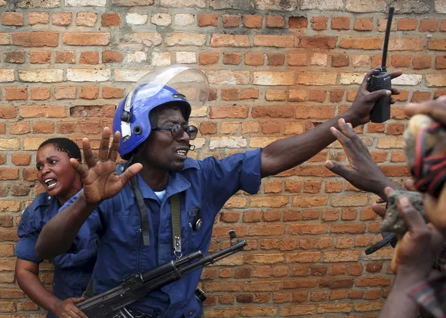 A policeman tries to protect a female police officer accused of shooting a protester in the Buterere neighborhood of Bujumbura, Burundi, May 12, 2015. Protesters opposed to the president's decision to run for a third term chased, beat and stoned the woman, who was later handed back to the police. (Photo by Goran Tomasevic/Reuters)