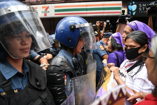 Women activists (R) face off with riot police who blocked their protest march towards the Malacanang Palace as they mark International Women's Day in Manila on March 8, 2024. (Photo by Ted Aljibe/AFP Photo)