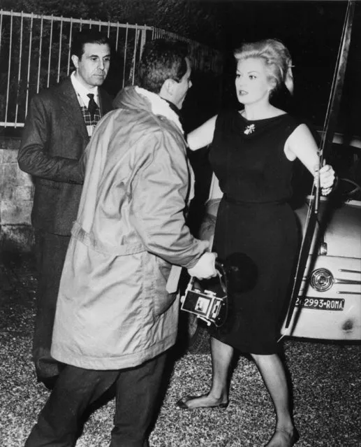 Swedish-born actress Anita Ekberg confronts Italian freelance photographer Felice Quinto with a bow and arrow outside her villa in Rome, Italy, late at night on October 19, 1960.  Ekberg quarreled with the photographer claiming she had been pursued all the time from the nightclub to her home.  Standing watching at left is film producer Guido Giambartolomeo. (Photo by Marcello Geppetti/AP Photo)