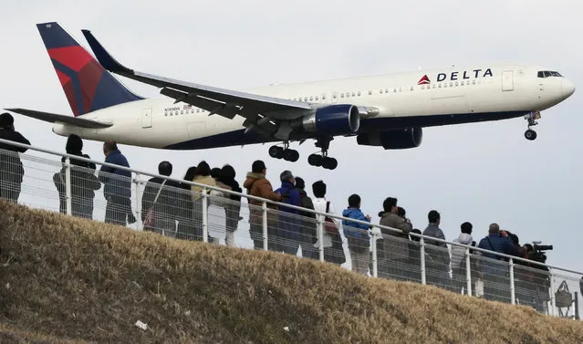 In this March 14, 2015, file photo, people watch a landing Delta Air Lines jet approach the Narita International Airport from a popular viewing spot at Sakuranoyama Park in Narita, east of Tokyo. (Photo by Koji Sasahara/AP Photo)