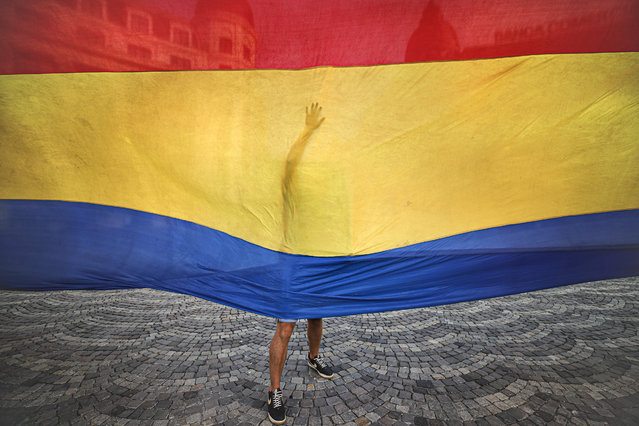 A youngster,  along with others, unfurls, a 100 meter- long Romanian flag as Romanians celebrate the national anthem day in Bucharest, Romania, Monday, July 29, 2019. (Photo by Vadim Ghirda/AP Photo)