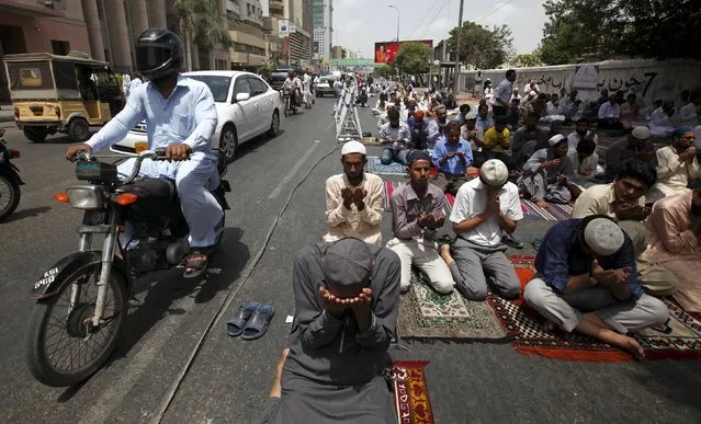 Vehicles move past men offering their Friday prayers near a mosque during the holy month of Ramadan in Karachi, Pakistan, July 3, 2015. (Photo by Akhtar Soomro/Reuters)