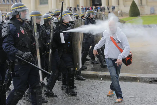French riot police officers sprays pepper gas at a demonstrator during a protest against Labor Law as the Socialist government decided to force the bill through Parliament without a vote, in Paris, Thursday, May 12, 2016. France's government is facing a major test as lawmakers hold a no-confidence vote, prompted by a deeply divisive labor law allowing longer workdays and easier layoffs. (Photo by Christophe Ena/AP Photo)