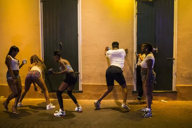 Revelers watch each other twerk to music from a nearby club along Bourbon Street, located in the French Quarter of New Orleans, Louisiana, July 11, 2015. (Photo by Adrees Latif/Reuters)