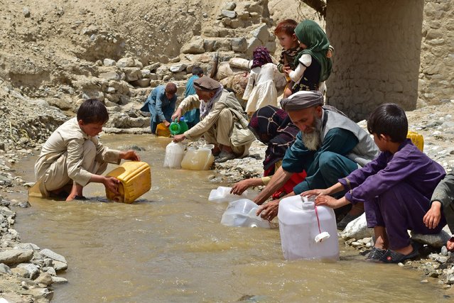 Afghans fill cans with water from a stream at a flood affected area in Burka district of Baghlan province on June 4, 2024. (Photo by AFP Photo)